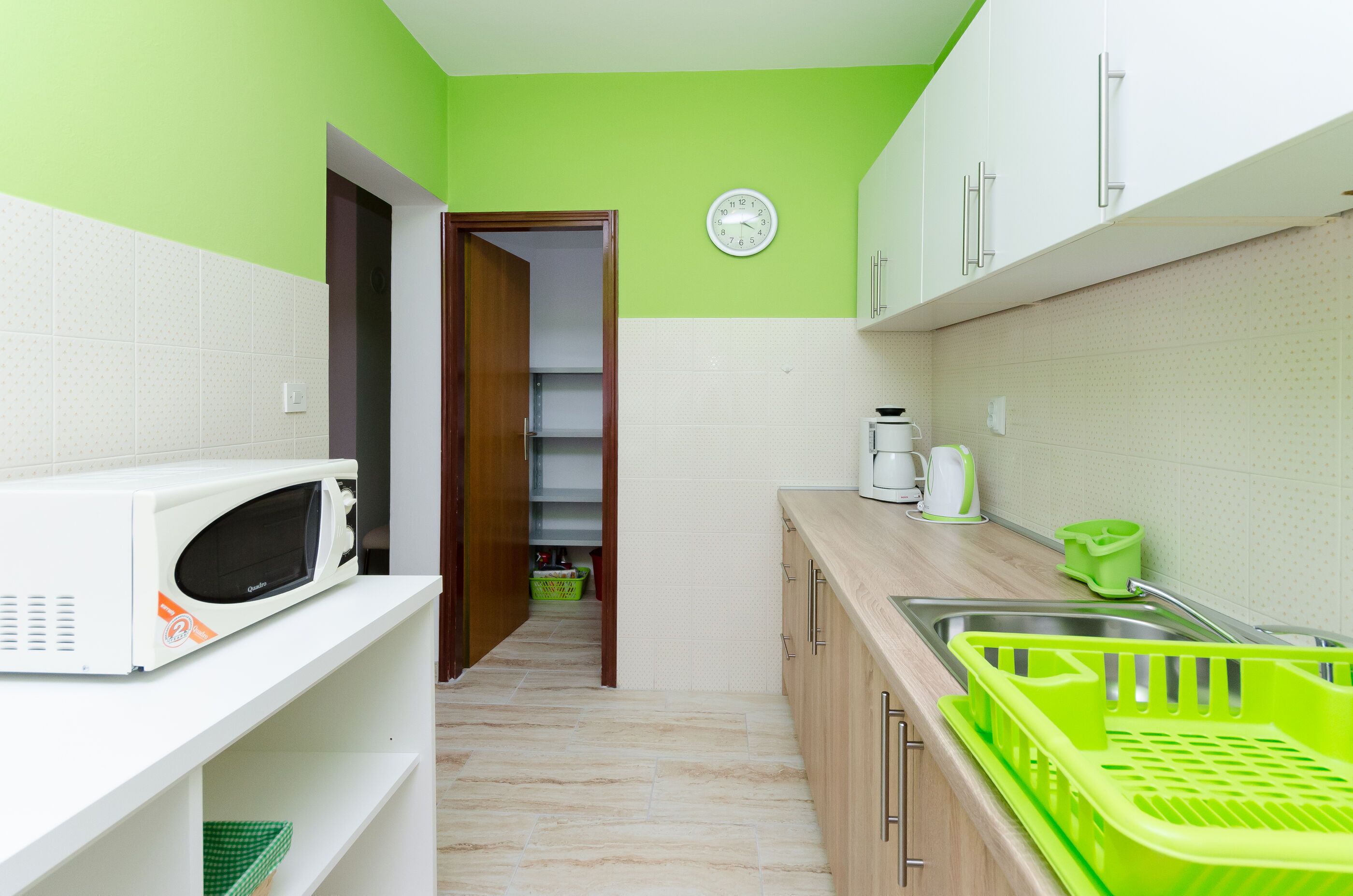 A kitchen with a microwave, sink, and green baskets.