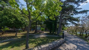 Un parco con un sentiero sterrato, un muro di pietra e alberi.