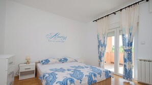 Un dormitorio con cama, mesita de noche, cómoda y ventana con cortinas.