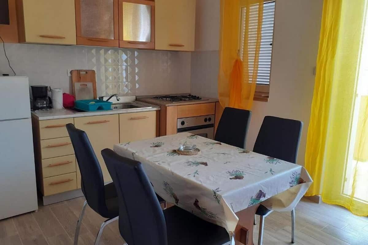 A compact kitchen with a dining table, chairs, and basic appliances.