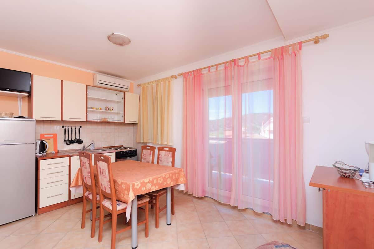A compact kitchen with a dining table, chairs, and a TV.