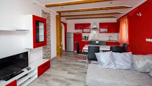 Una sala de estar moderna con una televisión de pantalla plana, un sofá y un comedor con una mesa y sillas.