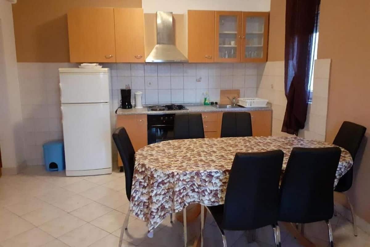 A compact kitchen with a dining table and chairs, a refrigerator, and a stove.