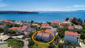 Ein Küstenwohngebiet mit Häusern, deren Dächer mit roten Ziegeln gedeckt sind, und Blick auf das Meer.