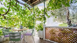 Eine Terrasse im Freien mit Tisch und Stühlen, umgeben von üppigem Grün und einem Spalierzaun.
