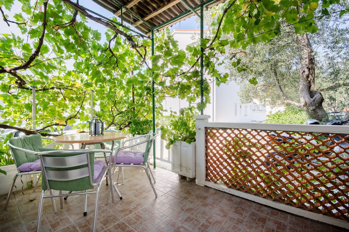 An outdoor patio with a table and chairs, surrounded by lush greenery and a lattice fence.