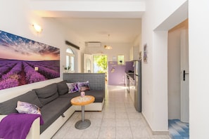 Una sala de estar moderna con un sofá, una pequeña mesa redonda y un cuadro grande de un campo de lavanda.