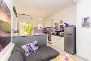 A modern kitchen with white cabinets, a stainless steel refrigerator, and a dining area with a table and chairs.
