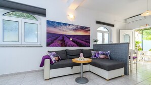 Ein modernes Wohnzimmer mit einem Ecksofa, einem runden Tisch und einem großen Landschaftsbild.