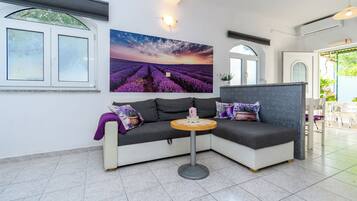 Una sala de estar moderna con un sofá seccional, una mesa redonda y un cuadro grande de paisaje.
