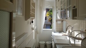 A narrow bathroom with a window, a sink, and a mirror. - Apartment Vesna (Lovran)