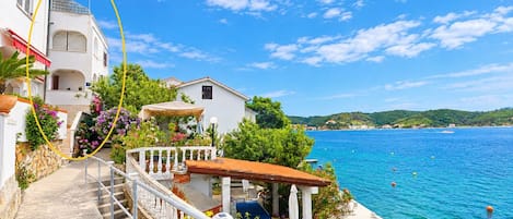 Um imóvel costeiro com escadaria que leva a um terraço com vista para o mar, piscina e visão da costa.