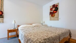 Un dormitorio con una cama, dos mesitas de noche, una lámpara y un adorno en la pared.
