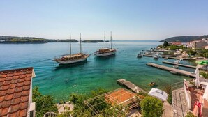 Una marina con barcos, agua cristalina y un pueblo costero al fondo.