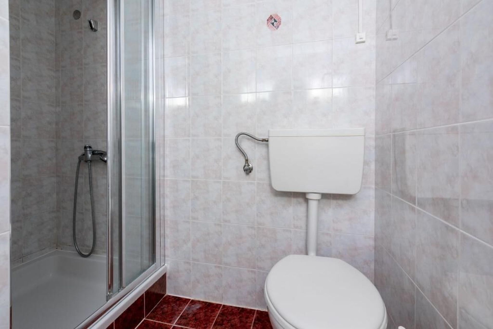 A bathroom with a shower, toilet, and tiled walls.