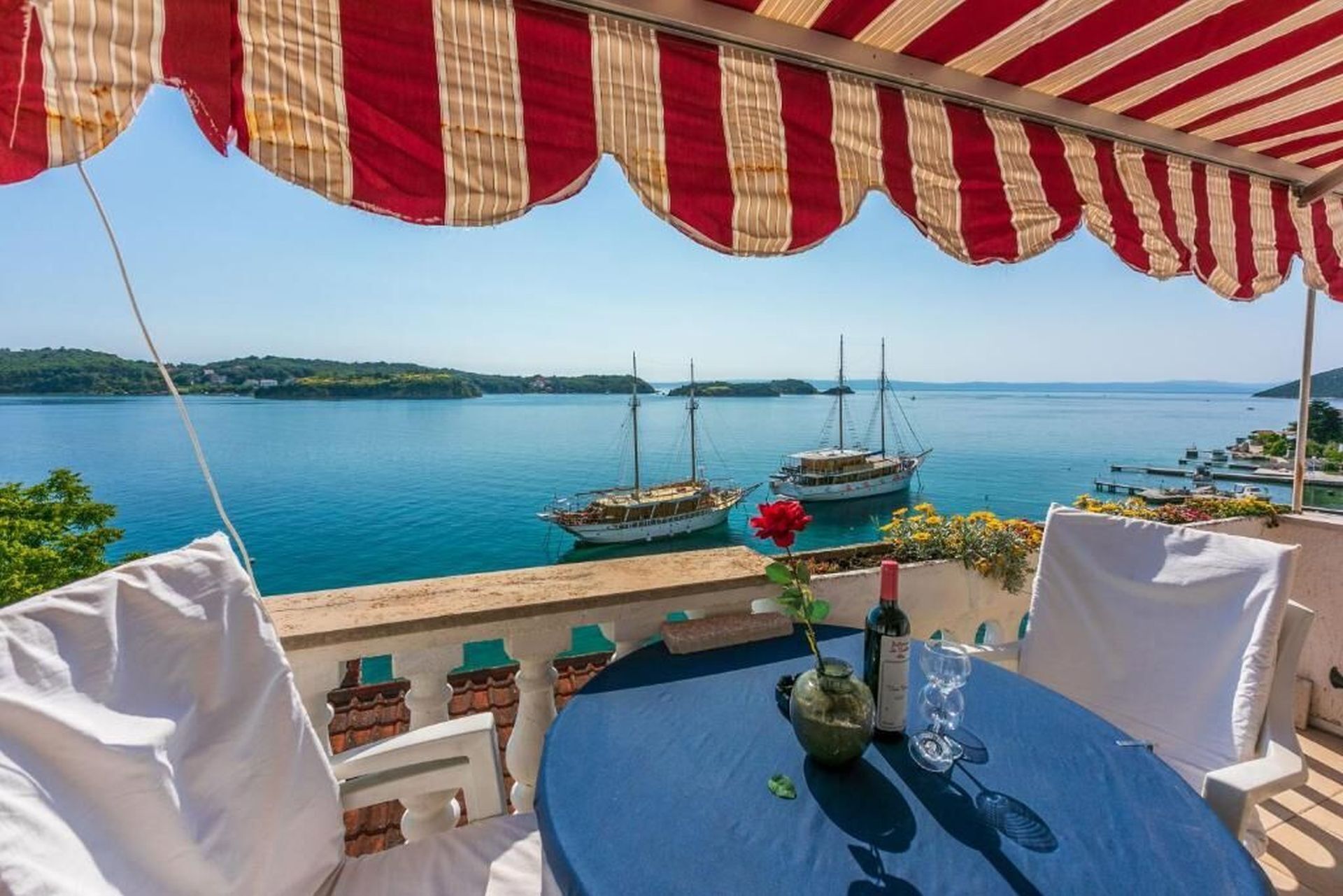 Una terraza con vistas a un mar tranquilo, con varias embarcaciones amarradas.
