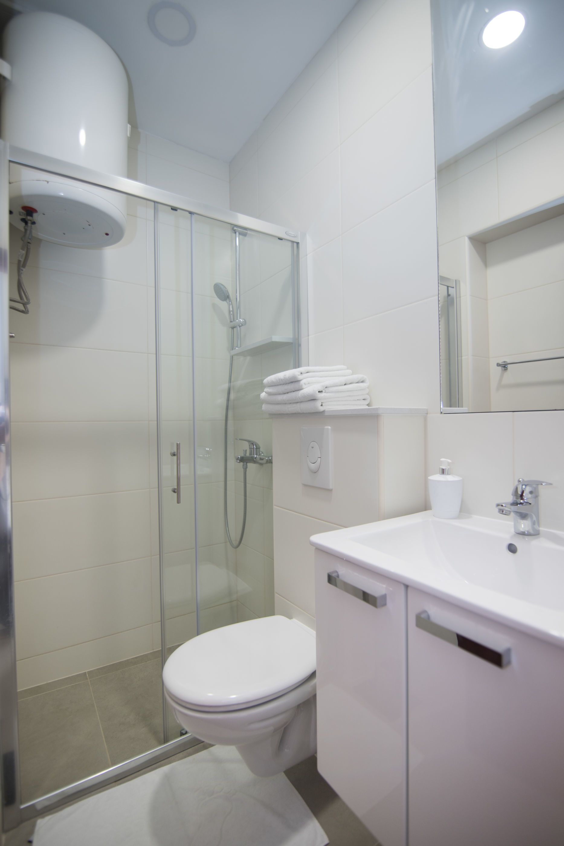 Un baño moderno con ducha envuelta en vidrio, inodoro blanco y tocador con espejo.