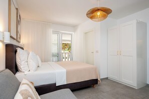 A bedroom with a bed, a sofa, a wardrobe, and a window with blinds. - Apartments and Rooms Kapulica (Tucepi)