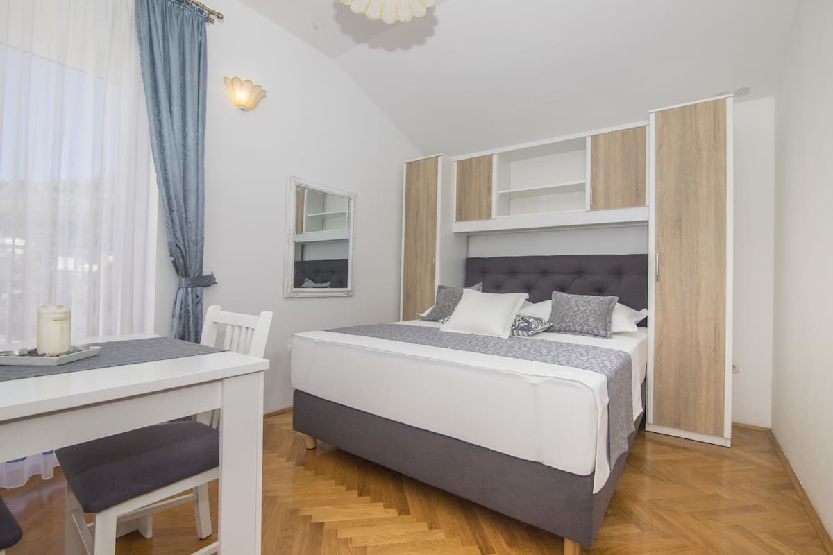 A bedroom with a bed, bedside tables, a desk, and a chair.