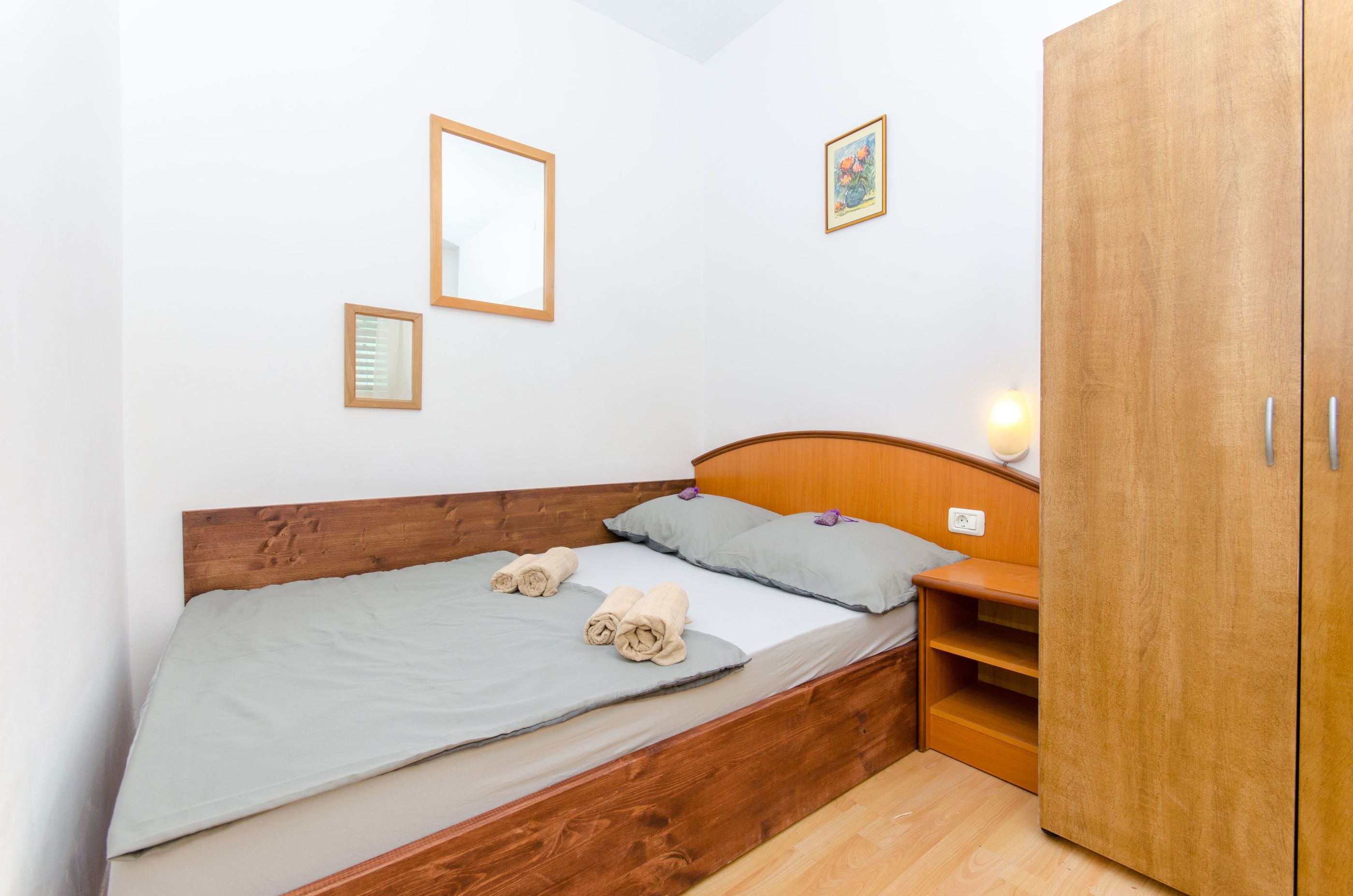 Un letto singolo con una testiera in legno, un comodino e un armadio.