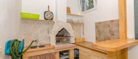 A compact kitchen with a stone backsplash, a built-in oven, and wooden countertops.