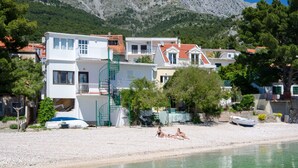 A coastal building with multiple balconies, a beach in front, and a mountain in the background. - House Beach House Toma (Zivogosce)