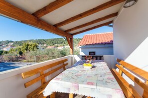 A balcony with wooden benches and a table covered with a floral tablecloth. - Apartments Rezika (Palit)