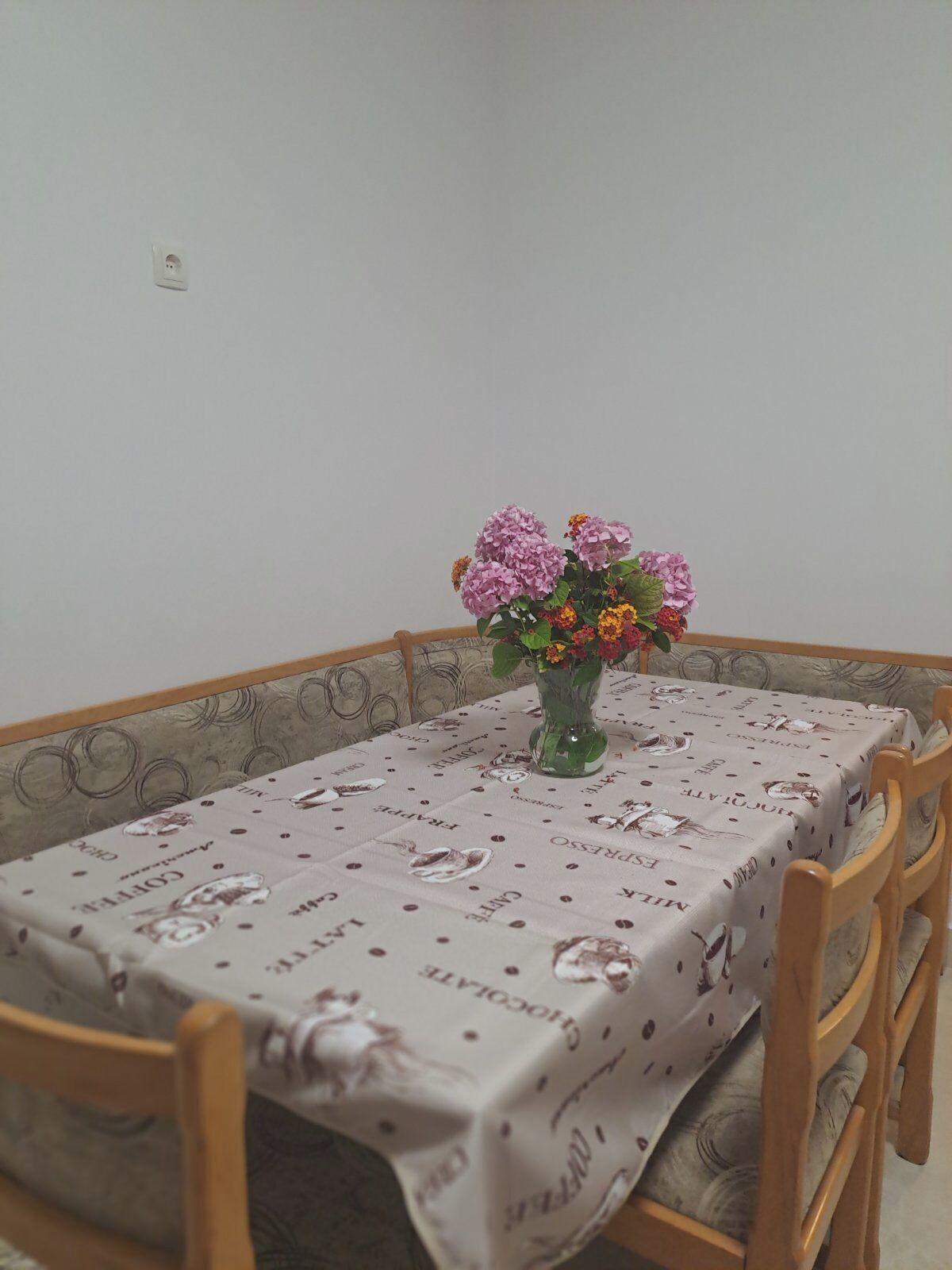 Ein Esstisch mit floralem Mittelstück, umgeben von Holzstühlen.