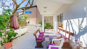 An outdoor patio with a table and chairs, a potted plant, and a building in the background. - Apartments Rezika (Palit)