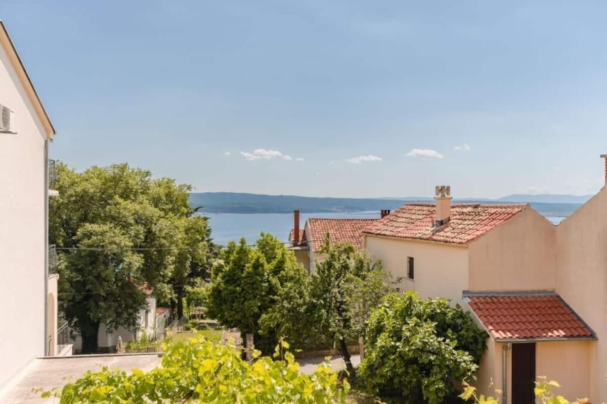 A coastal residential area with houses, greenery, and a view of the sea.