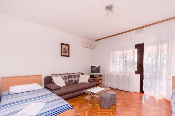 A bedroom with a bed, a sofa, a TV, and a window with curtains. - Apartments Nenad (Dramalj)