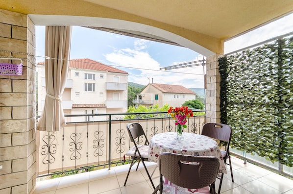 Ein Balkon mit Tisch, Stühlen und einem Blumenstrauß.