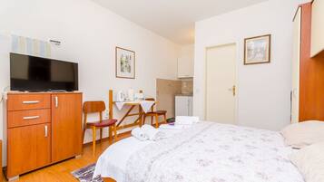 Une chambre d’hôtel comprenant un lit, un bureau avec une chaise, une télévision et une kitchenette.