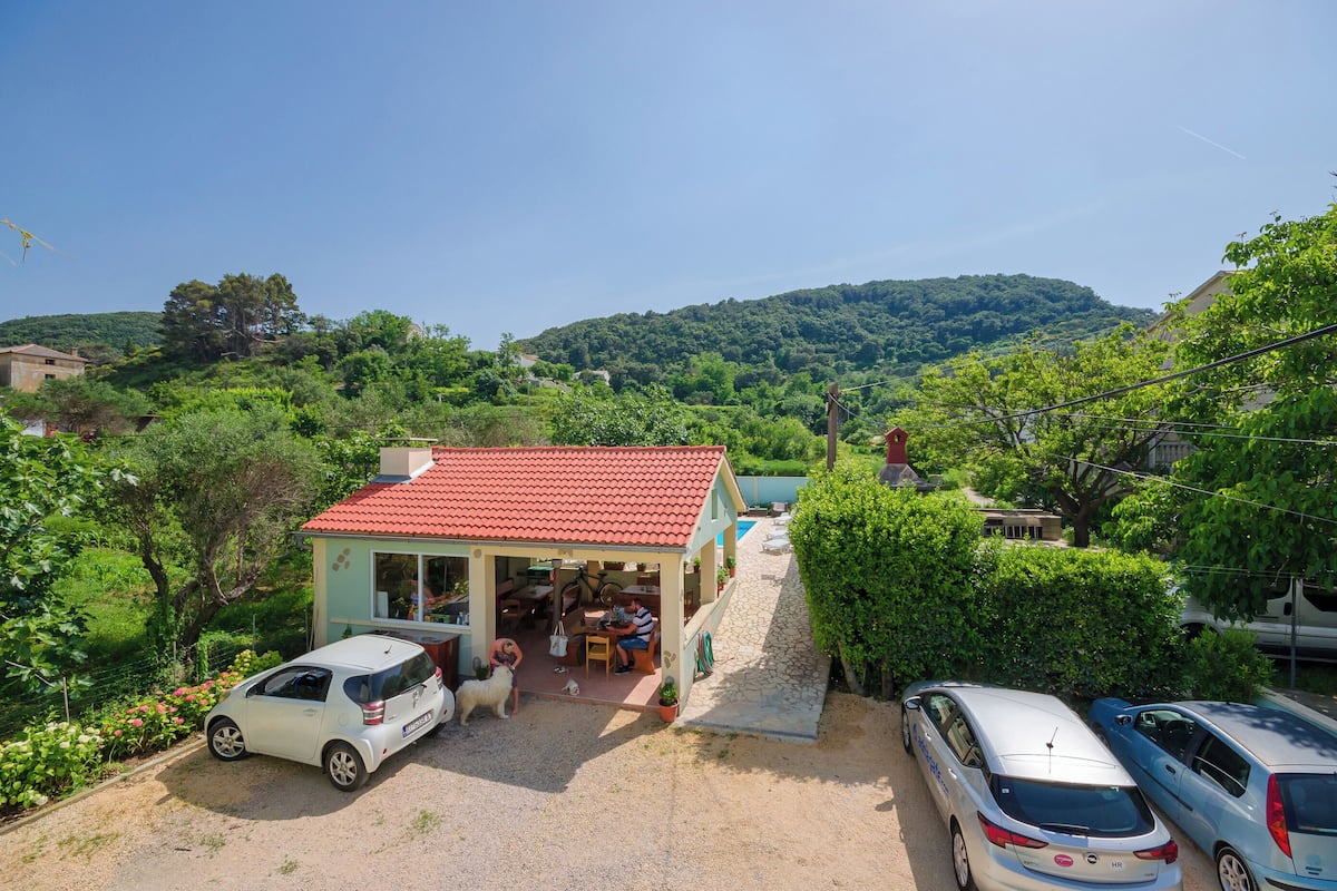 A small house with a red roof, a patio, and a car parked in front.