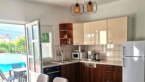 Une cuisine moderne avec un coin repas, de grandes fenêtres et une vue sur une piscine.