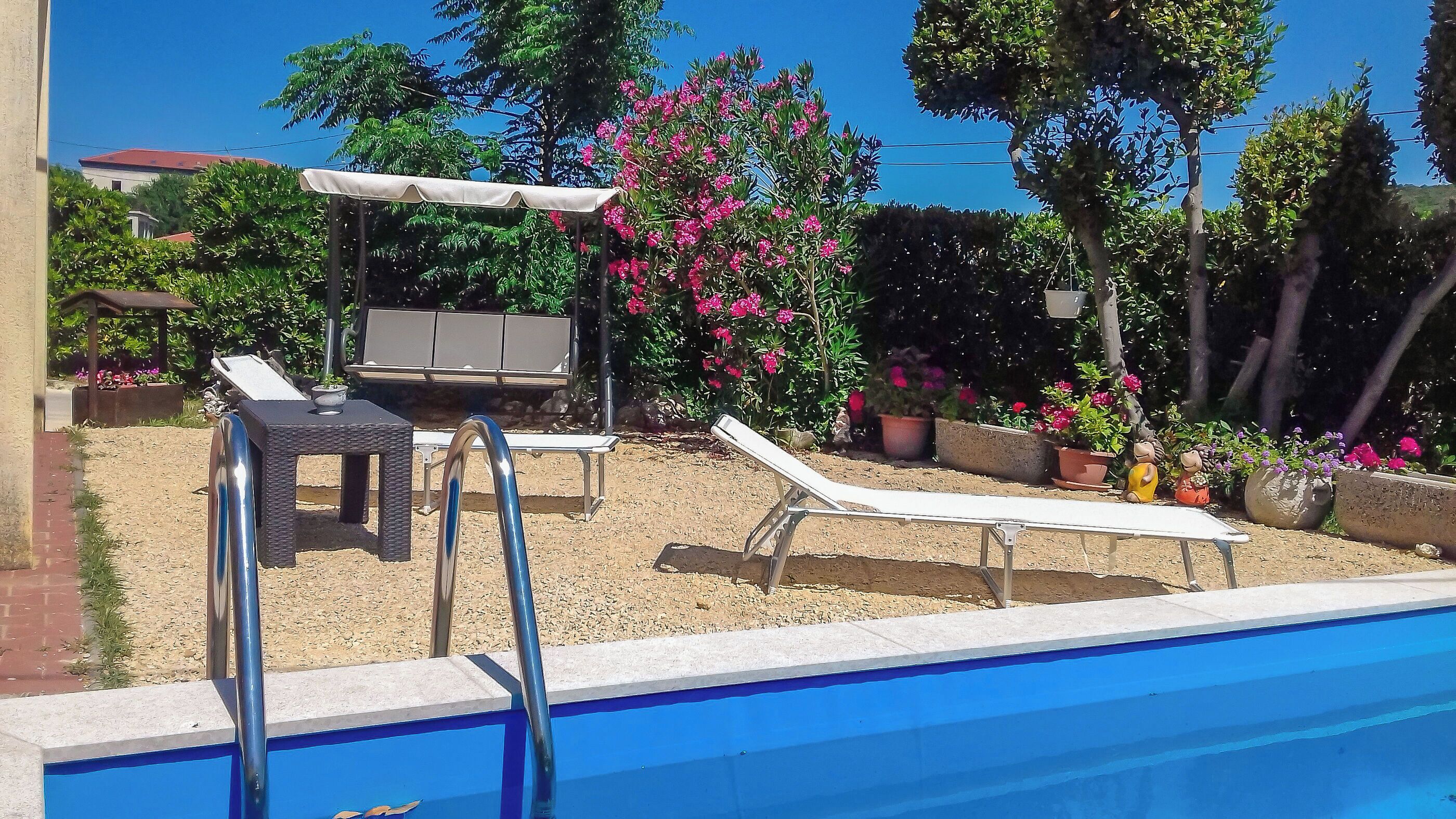 A swimming pool with lounge chairs and a covered seating area.