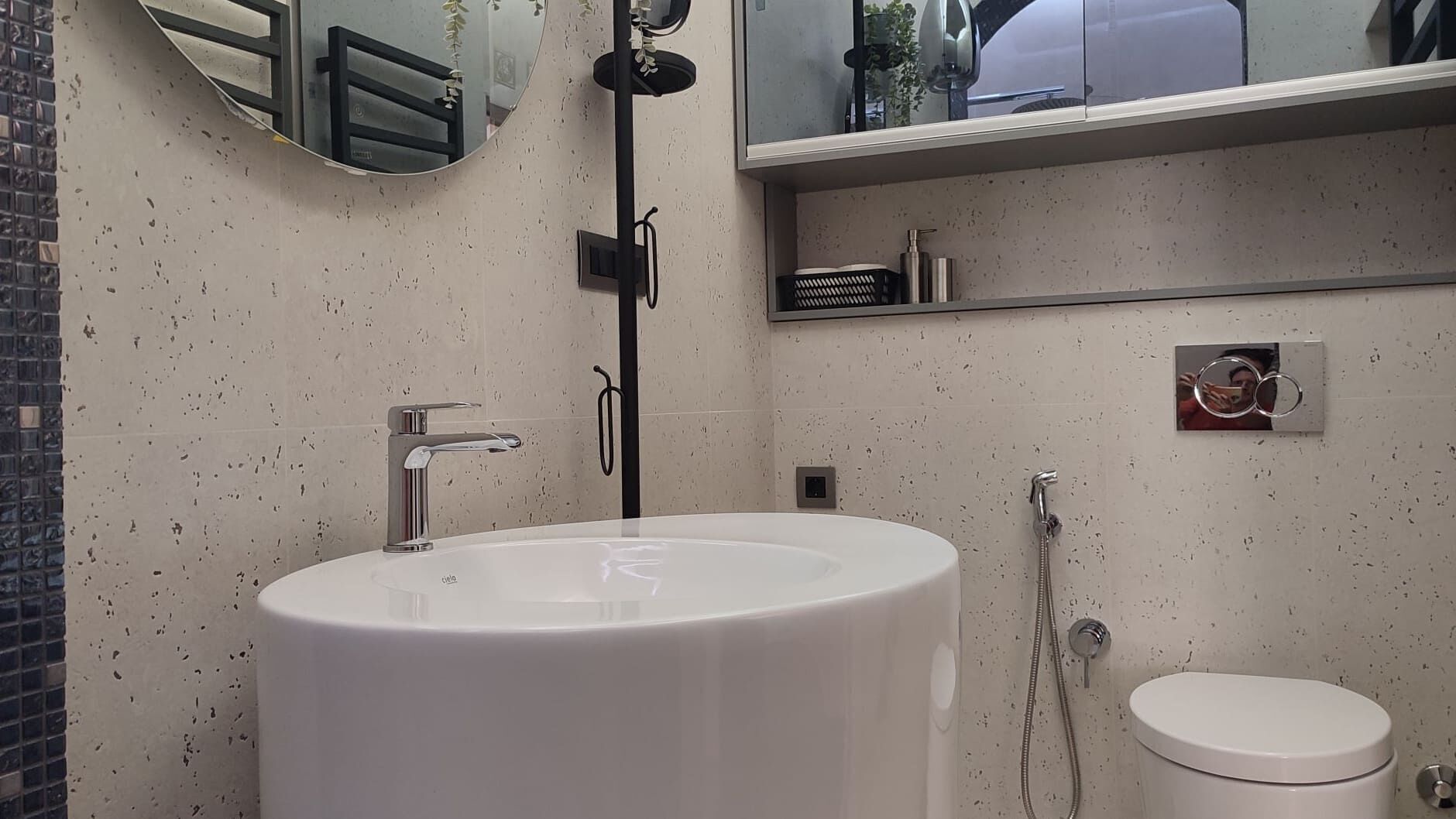 A bathroom with a white sink, a toilet, a mirror, and a shower.