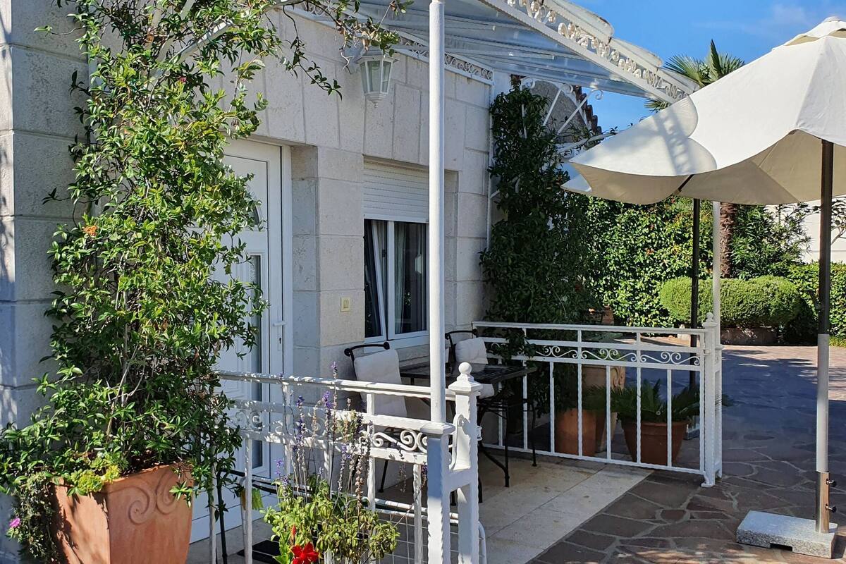 Ein Balkon mit weißer Brüstung, einem Tisch, einem Stuhl und einem Blumentopf.