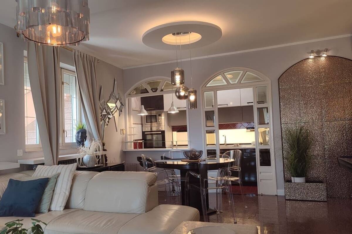 Ein modernes Wohnzimmer mit Sofa, Essbereich, Küche und einer Wandverkleidung.