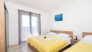 A hotel room with two beds, a large window with curtains, a painting on the wall, and a bedside table with a lamp. - Apartment Summerteracea (Vodice)
