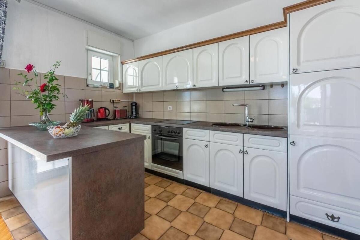 Una cocina moderna con armarios blancos, una isla central y un salpicadero de azulejos.
