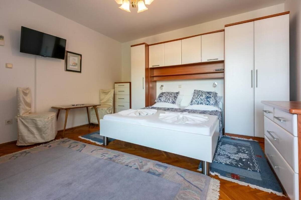 Un dormitorio con cama, televisor montado en la pared, escritorio y armario.