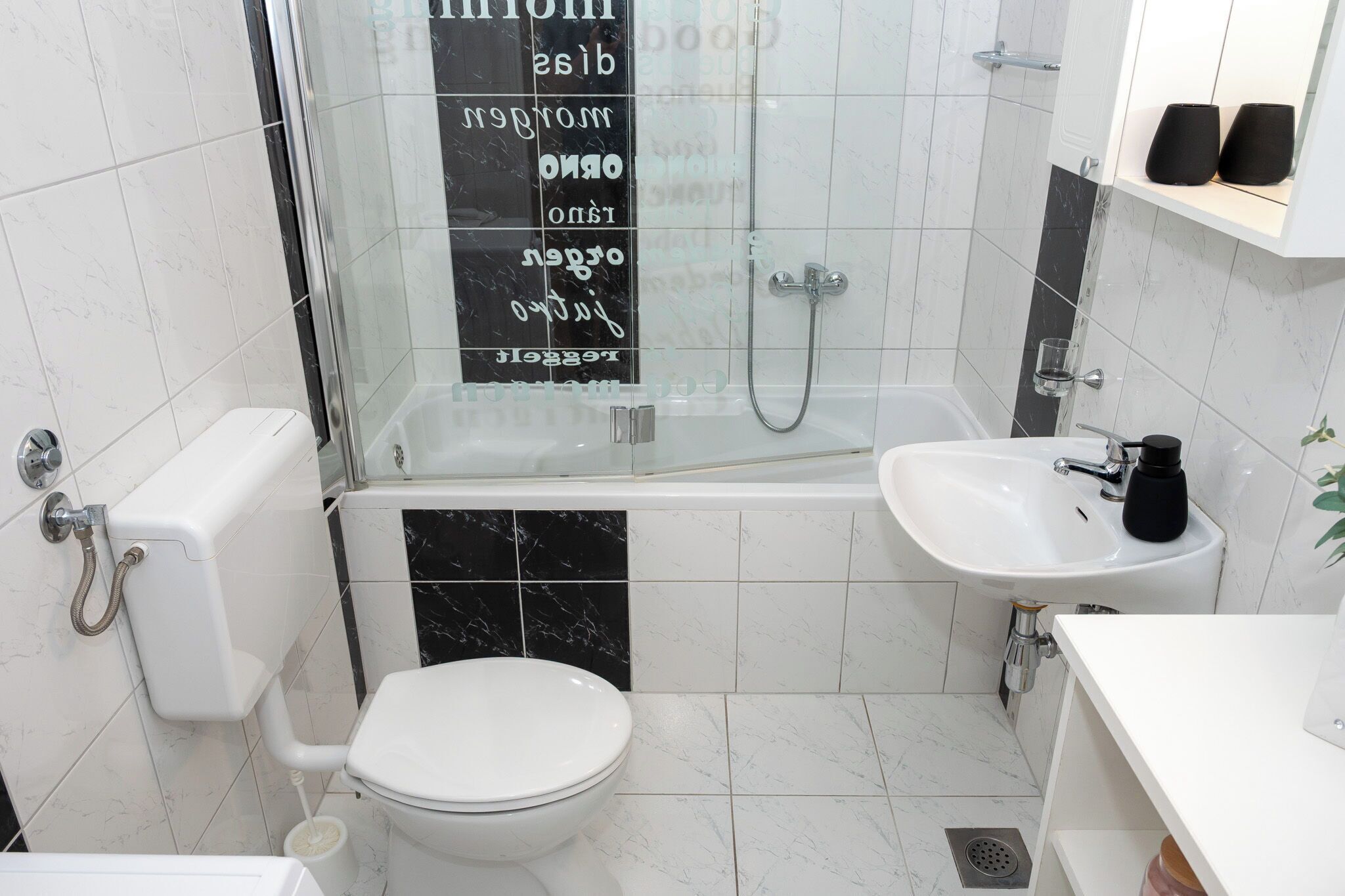A bathroom with a toilet, shower, and sink.