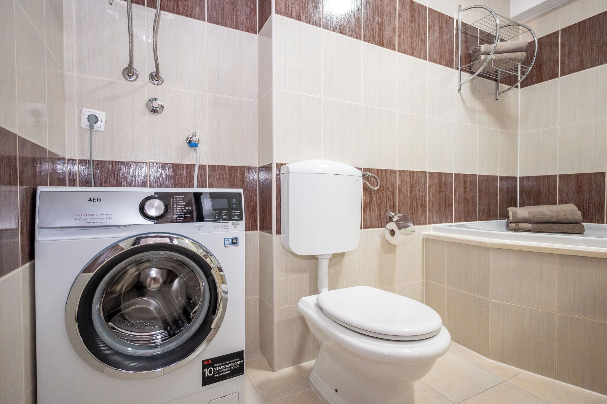 A compact bathroom with a washing machine, toilet, and bathtub.