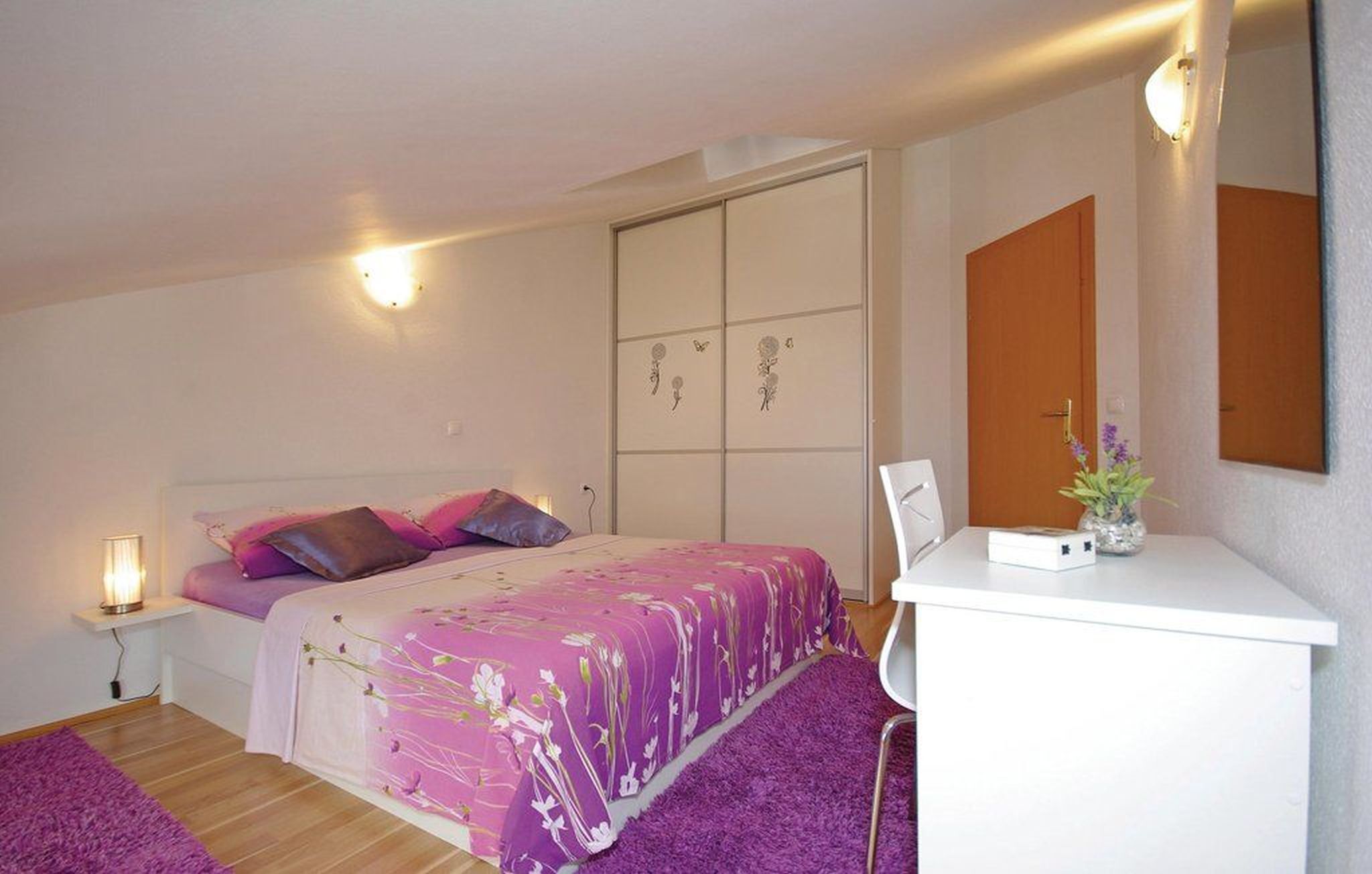 A bedroom with a bed, bedside table, and a mirror.
