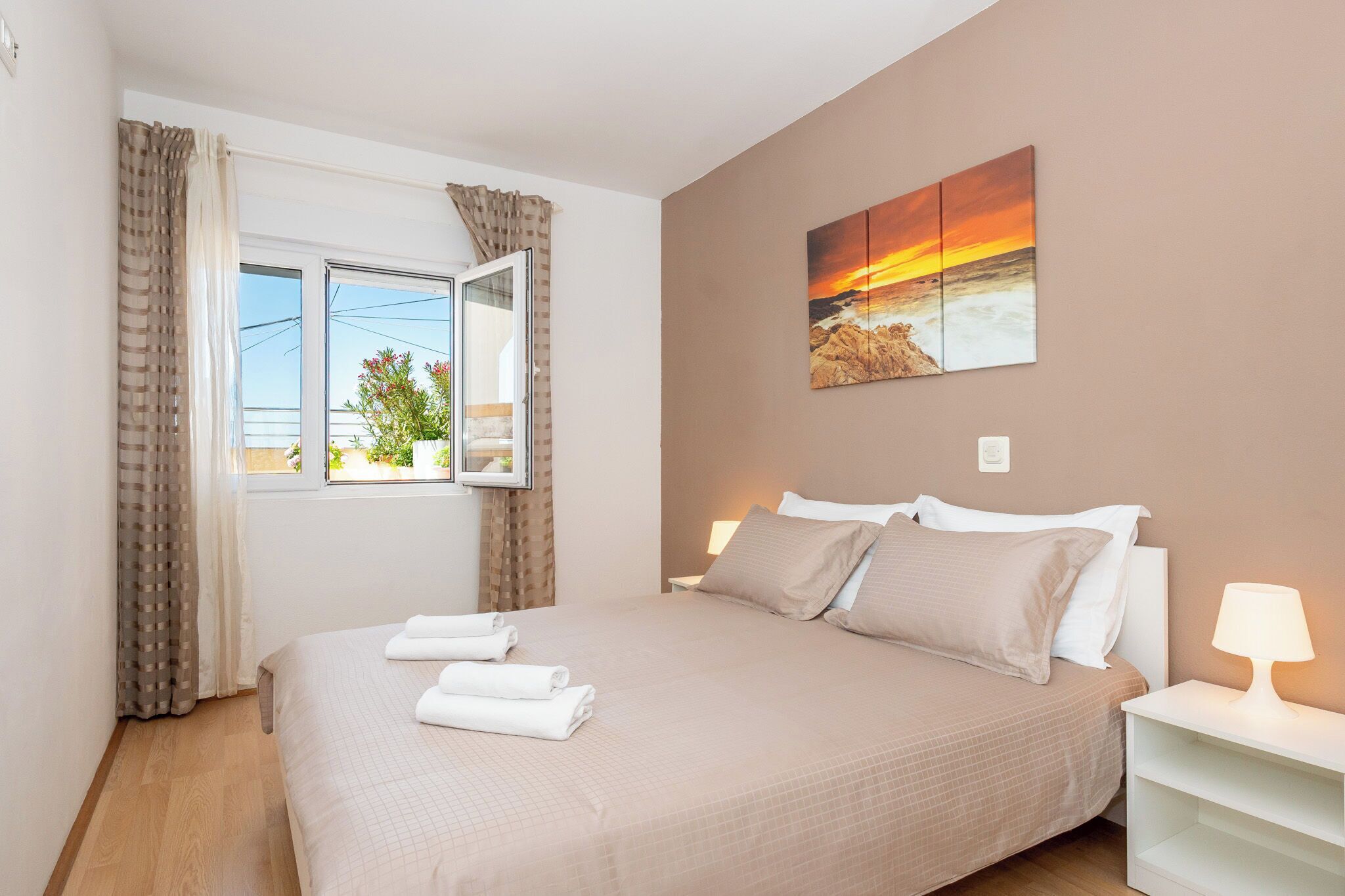 Une chambre à coucher avec un lit, des rideaux, une fenêtre, un tableau accroché au mur et une lampe de chevet.