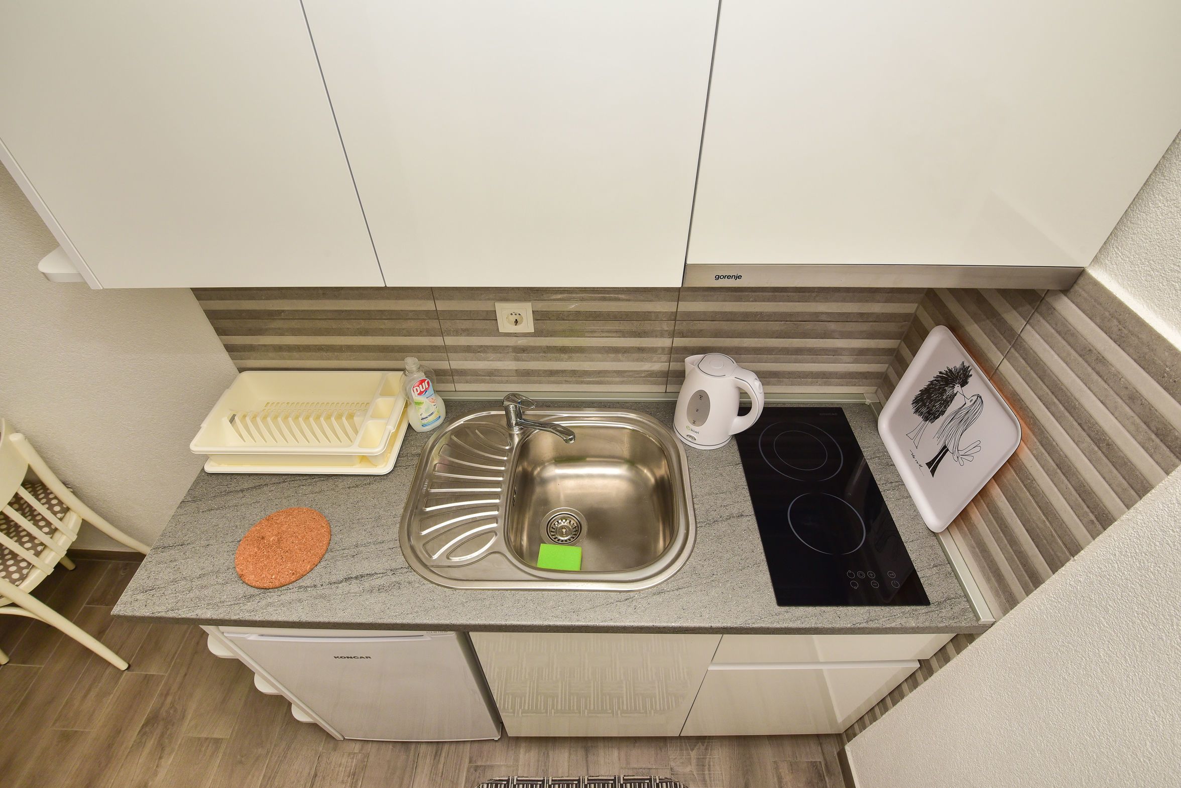 Une cuisine compacte équipée d’un évier, d’une bouilloire et d’une cuisinière.