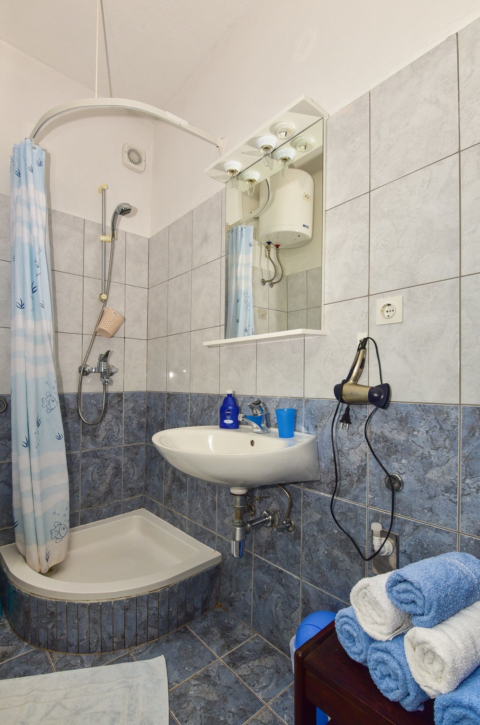 Un bany amb dutxa, un lavabo i un mirall.