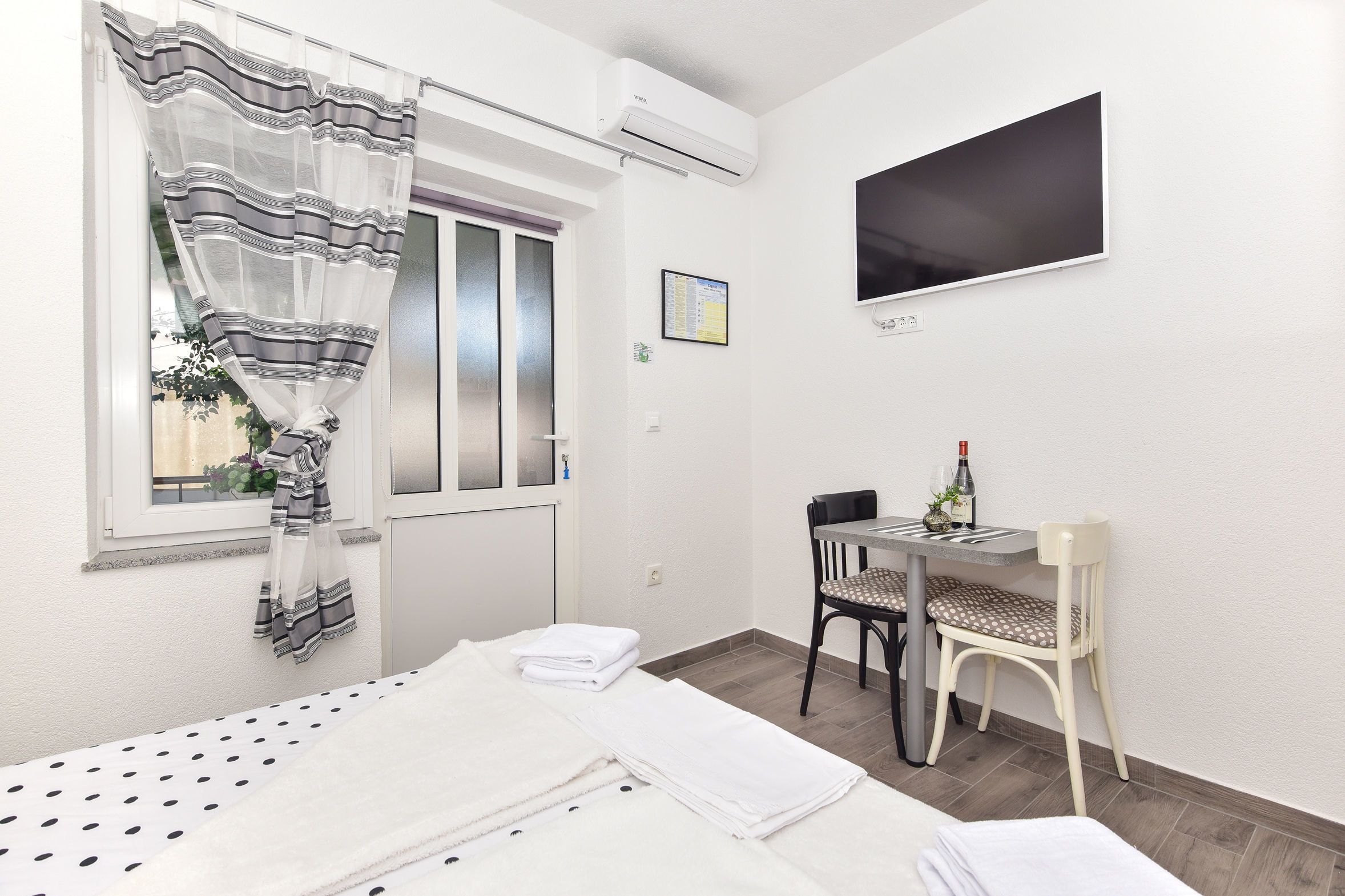 A hotel room with a bed, a desk with a chair, a TV, and a window with curtains.