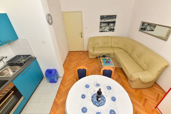 A compact living space with a kitchen, a sofa, a dining table, and a small coffee table. - Apartments Bernarda (Makarska)